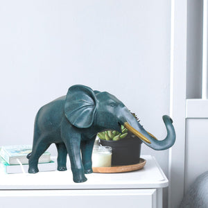 Blue bronze elephant statue on bookshelf beside books and desk accessories as office decor accent
