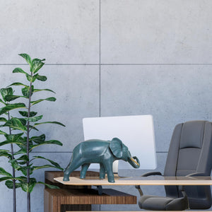 Blue bronze elephant statue on bookshelf beside books and desk accessories as office decor accent