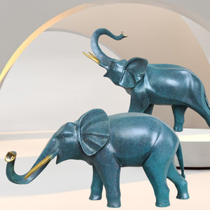 Pair of cerulean blue bronze elephant statues displayed on desk beside plant as modern home decor