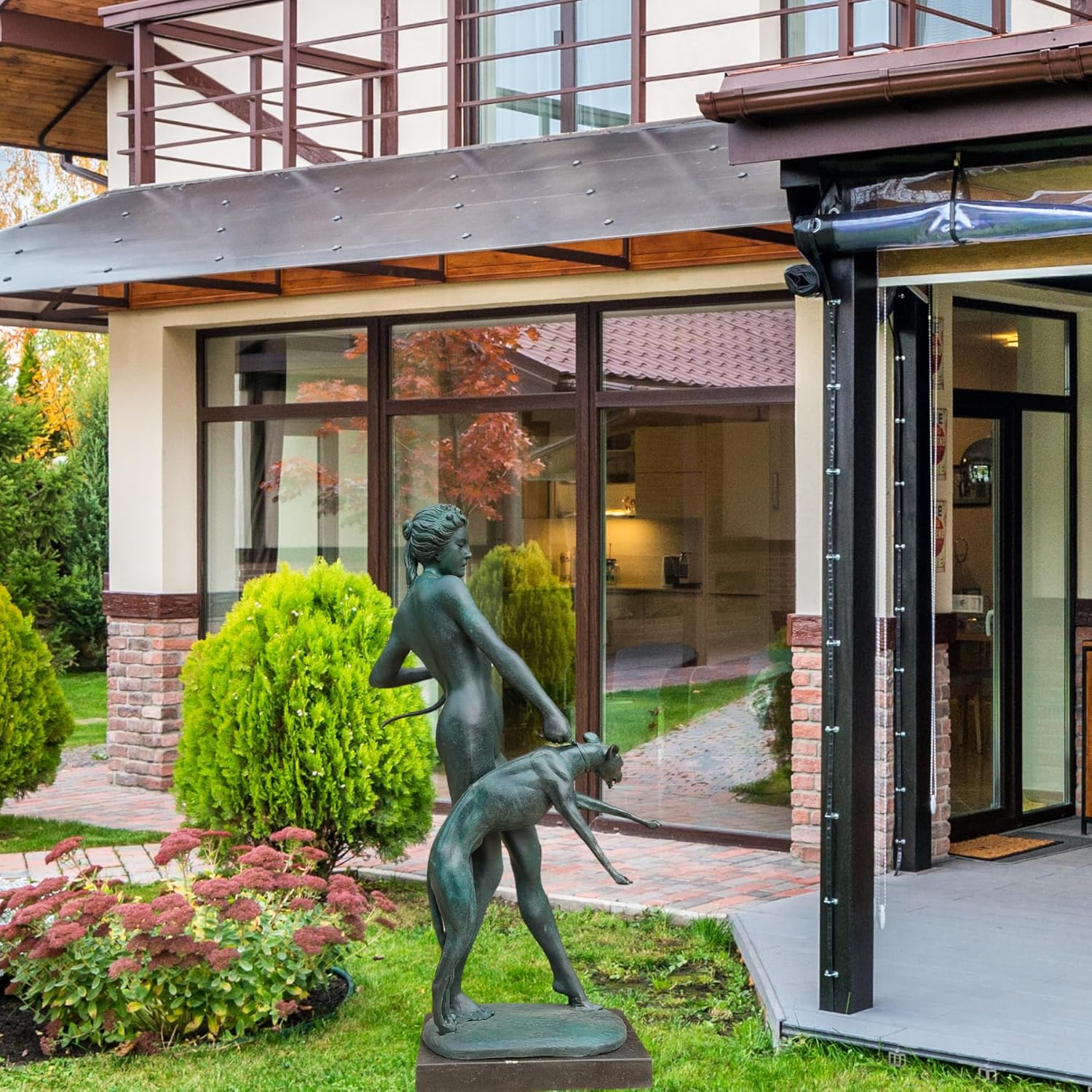 Large bronze Artemis goddess statue displayed on garden lawn outside luxury villa