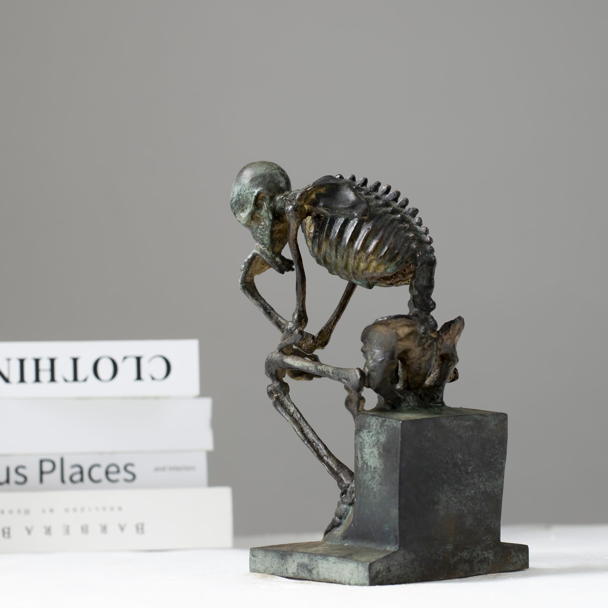 Bronze skeleton Thinker statue displayed on wooden table in modern interior room setting