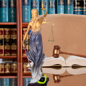 Bronze Lady Justice Themis statue in law firm office with law books and gavel display back 
