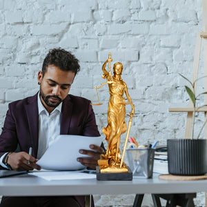 Bronze Lady Justice Themis statue on desk during male and female attorney consultation in law office