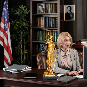 Bronze Lady Justice Themis statue in law office during female lawyer and client consultation meeting