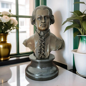 Bronze Mozart bust statue displayed with plant near window in indoor setting