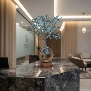 Handcrafted bronze olive tree sculpture on a granite reception counter in a modern luxury commercial office lobby.