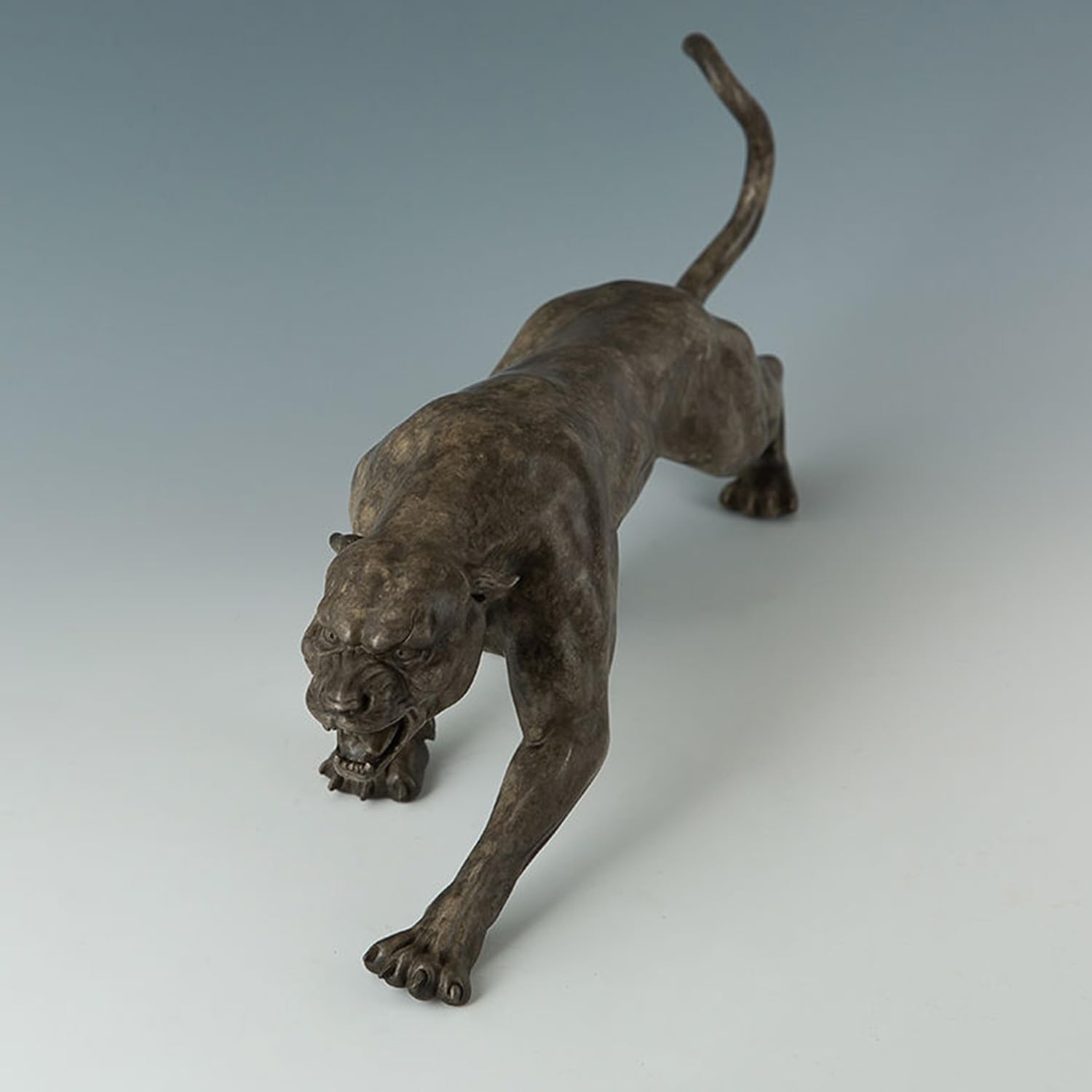 Close-up detail of bronze stalking panther statue with open roaring mouth and textured surface