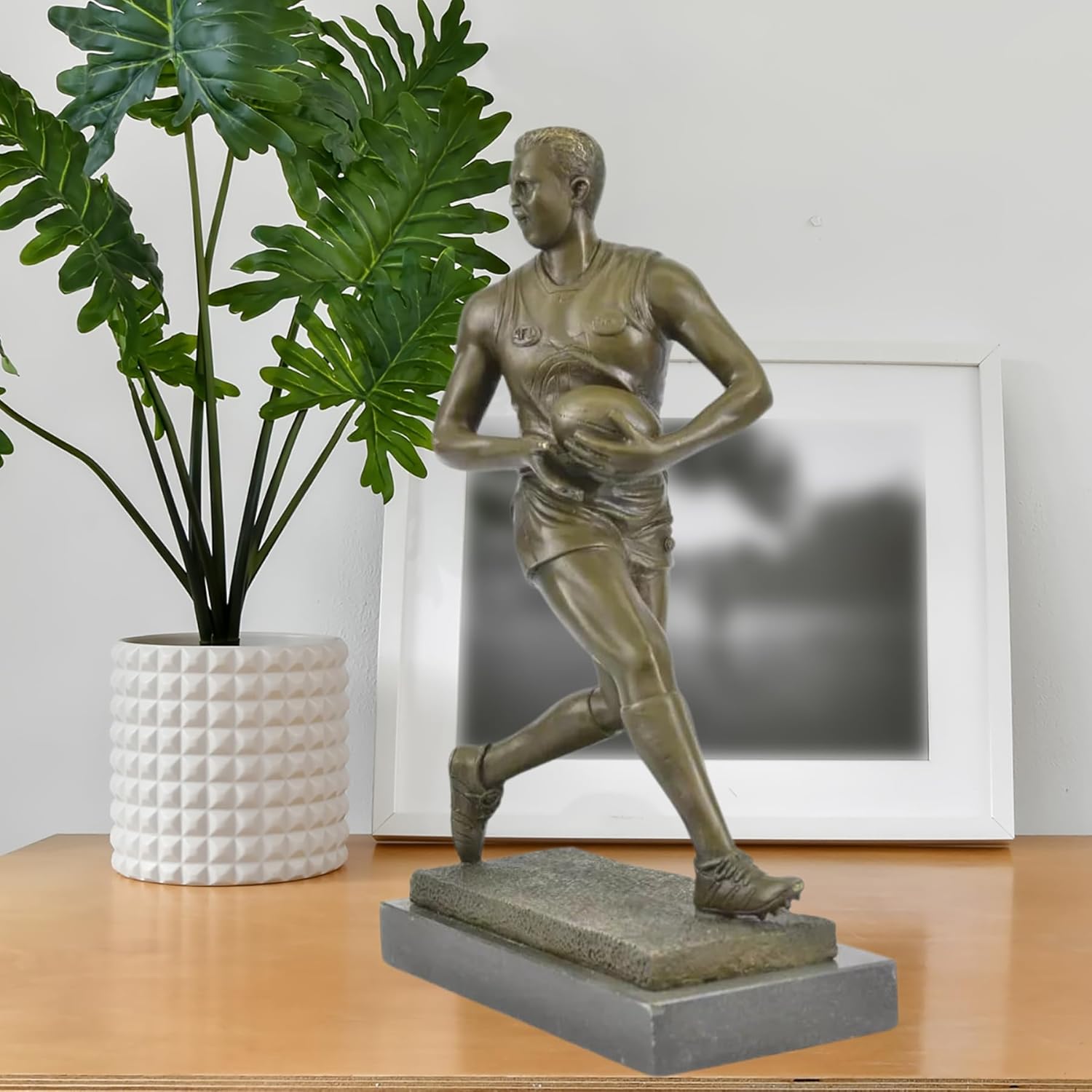 Bronze rugby player sculpture displayed in modern living room as sports décor centerpiece