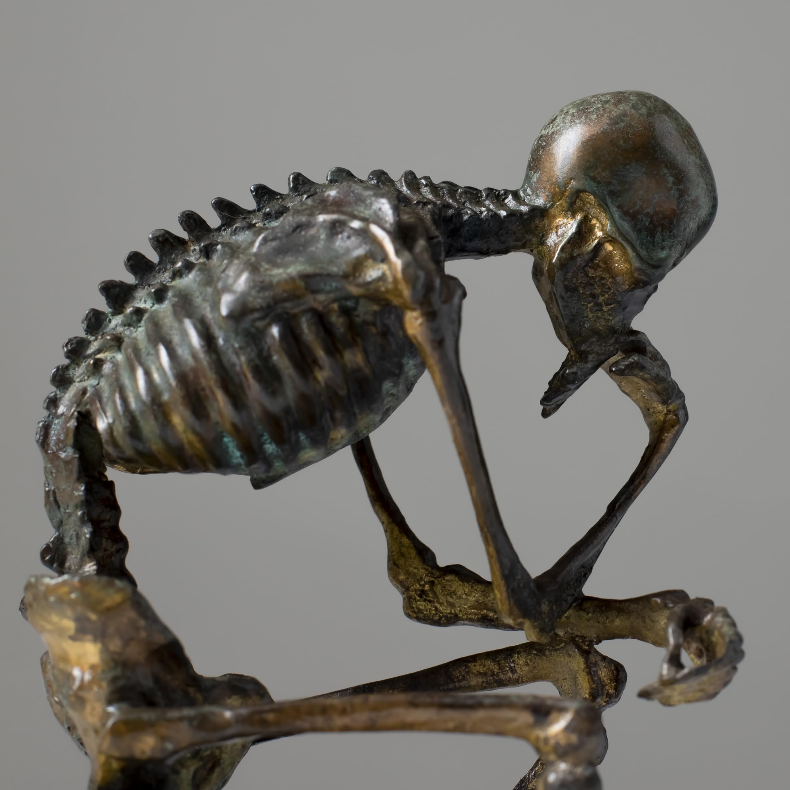 Bronze skeleton Thinker statue in antique grey bronze finish front view on white background