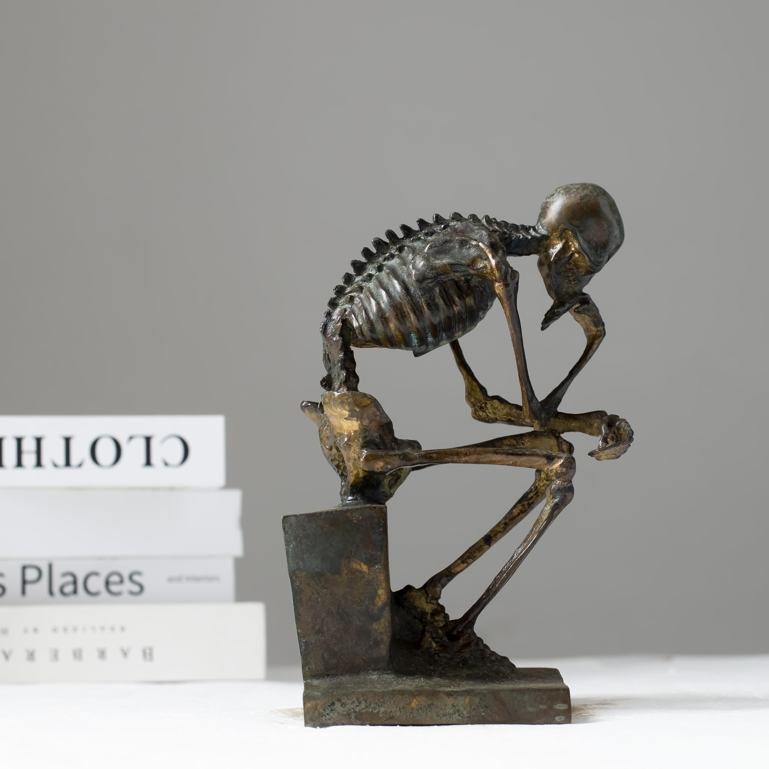Close-up of bronze skeleton Thinker statue in antique grey finish showing detailed seated skeletal pose
