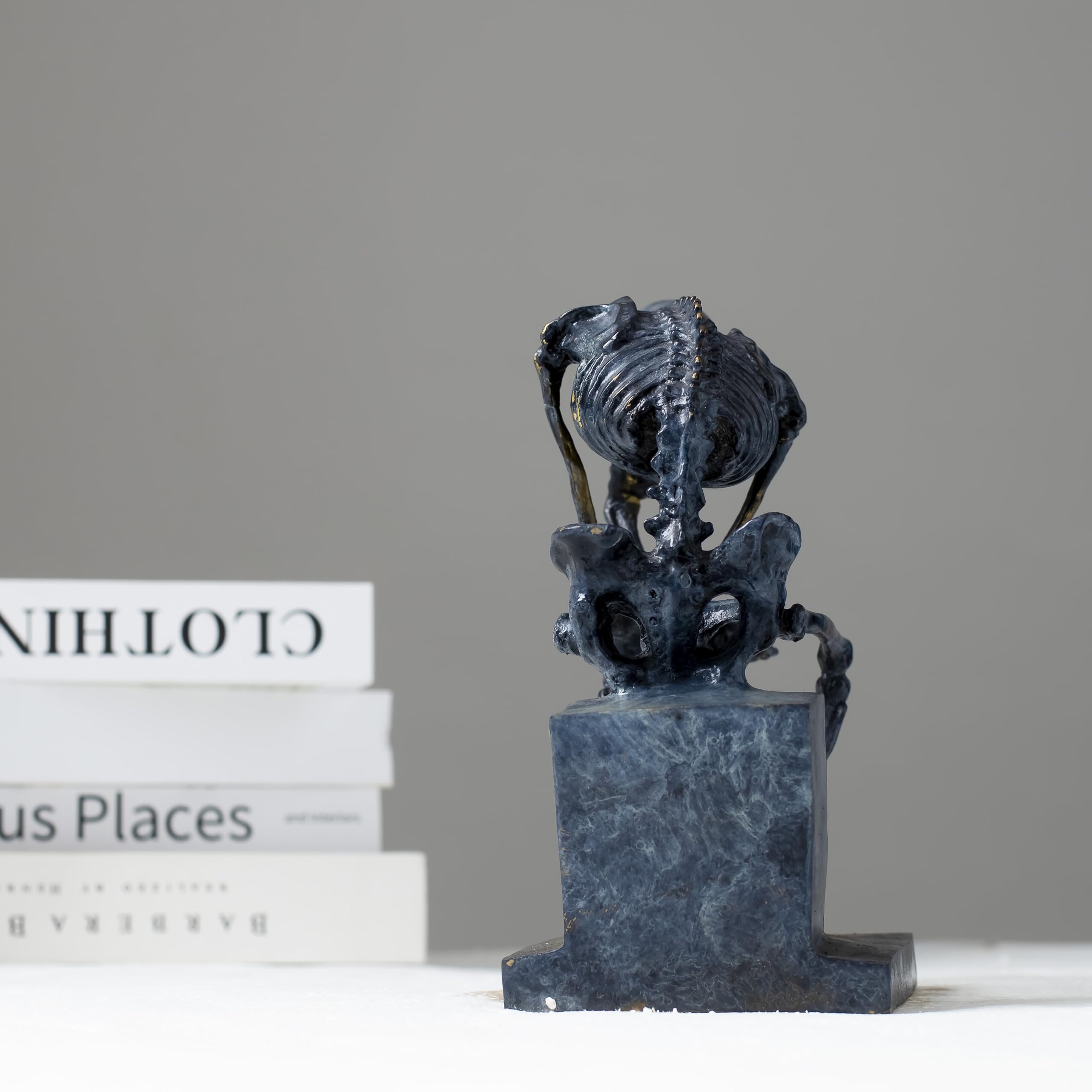 Close-up top view of bronze skeleton Thinker statue in blue-grey patina showing detailed skull and spine