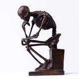 Bronze skeleton Thinker statue in brown bronze finish front view on white background