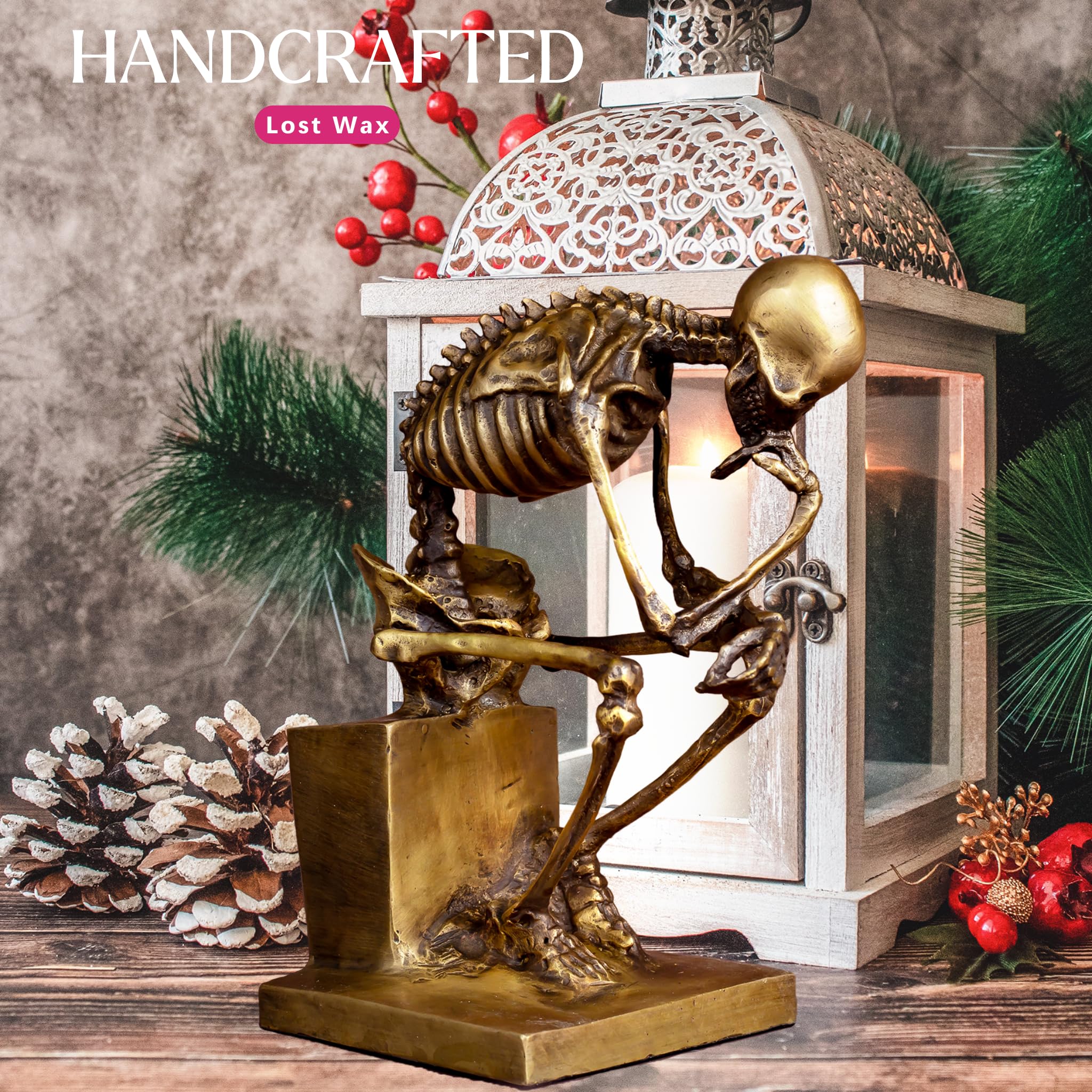 Bronze skeleton Thinker statue in gold finish handcrafted feature beside pinecone holiday decor