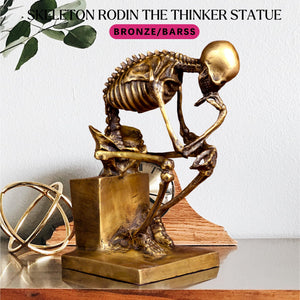 Bronze skeleton Thinker statue in gold finish beside plant and decorative vase