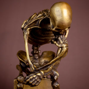 Bronze skeleton Thinker statue product feature card on warm brown background showing detailed pose