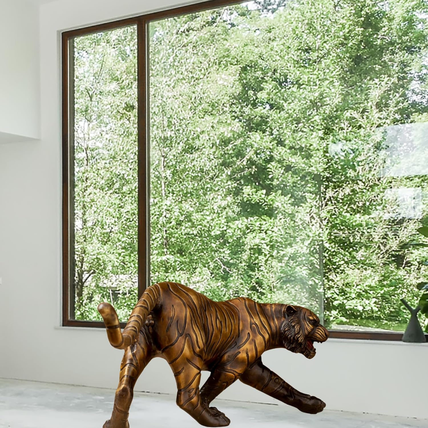 Bronze tiger statue displayed beside large window natural light interior