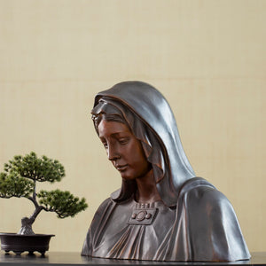 Bronze Virgin Mary bust statue displayed with bonsai tree, front angle view in indoor setting