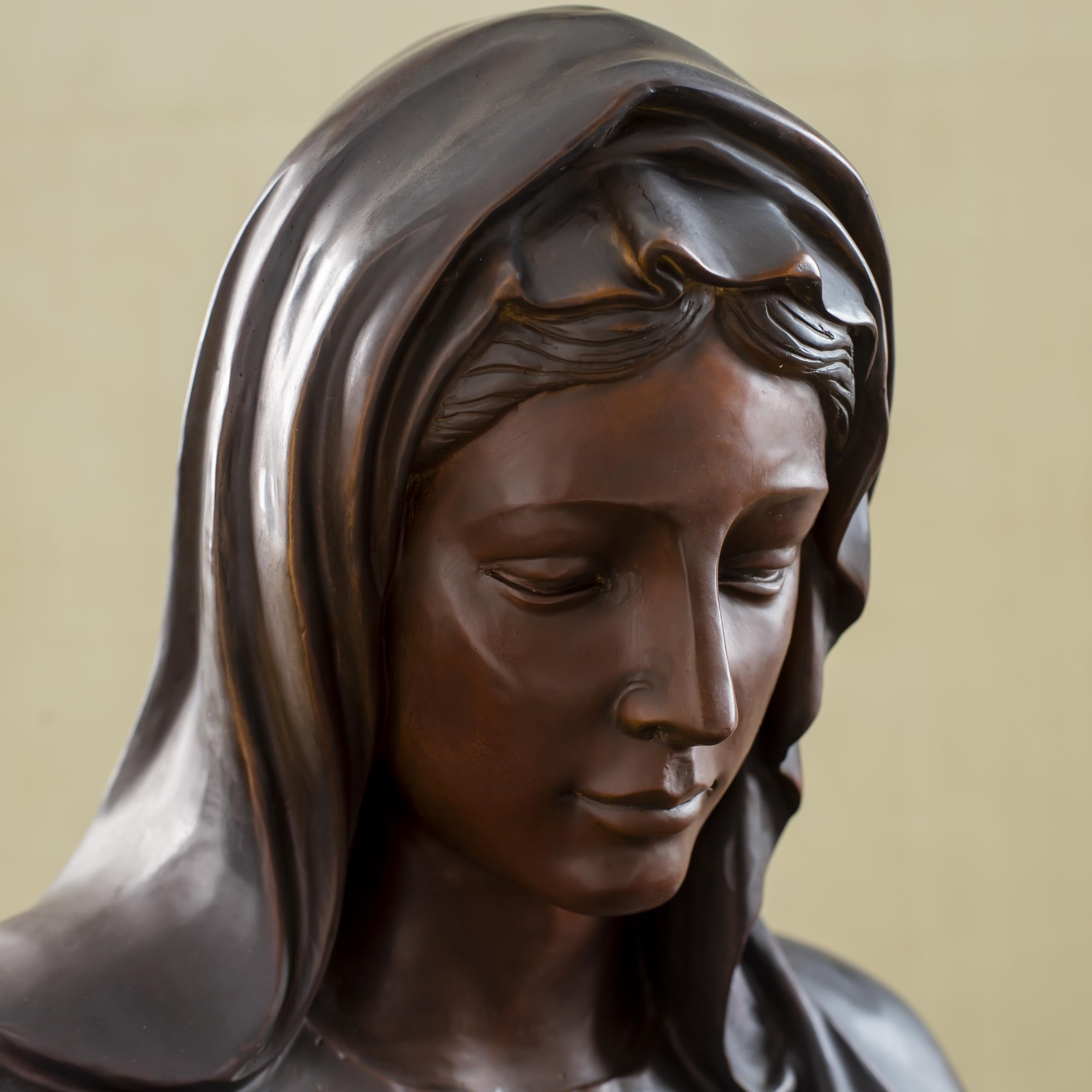 Close-up detail of bronze Virgin Mary bust statue showing contemplative downward gaze and facial detail