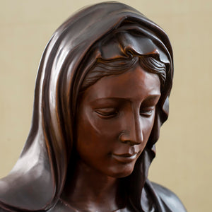 Close-up detail of bronze Virgin Mary bust statue showing contemplative downward gaze and facial detail