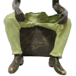 Rear angle view of Les Voyageurs seated fragmented bronze figure with green trouser detail