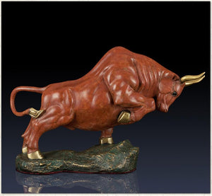 Handcrafted orange-red charging bull statue, front view.