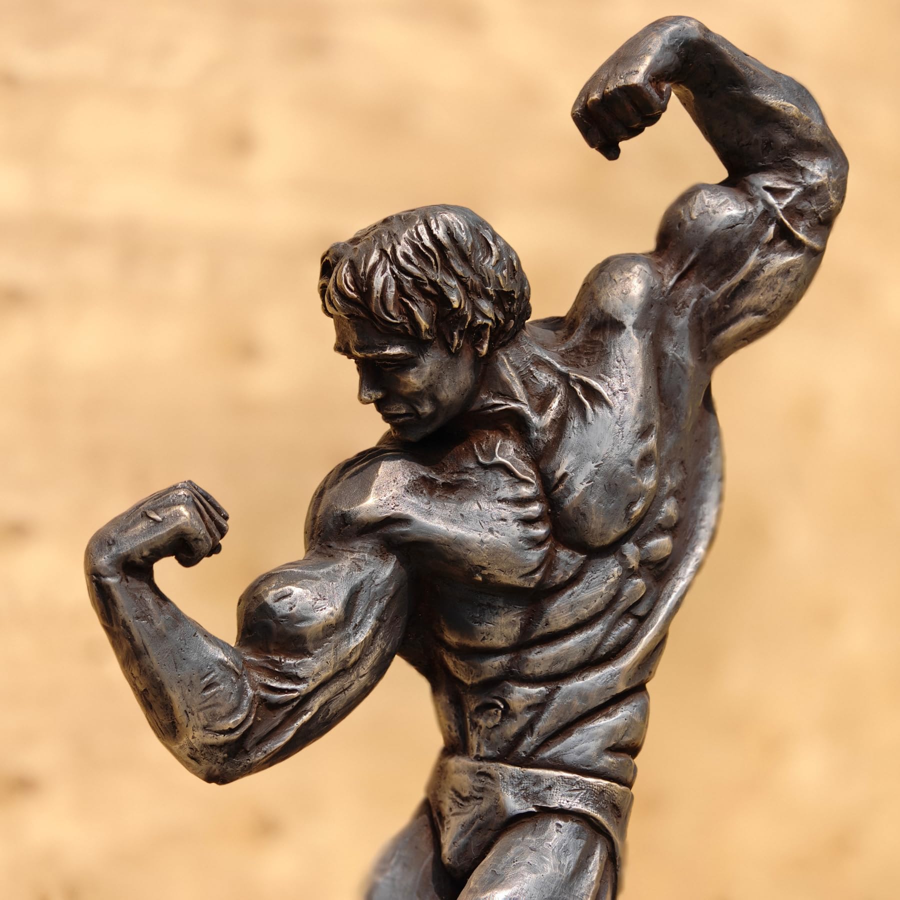 Close-up of dark patina bodybuilder bronze sculpture highlighting detailed muscle anatomy