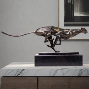 Dark bronze running cheetah sculpture on black marble base displayed on marble table luxury interior