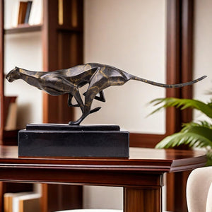 Dark bronze running cheetah sculpture on black marble base displayed on marble table luxury interior