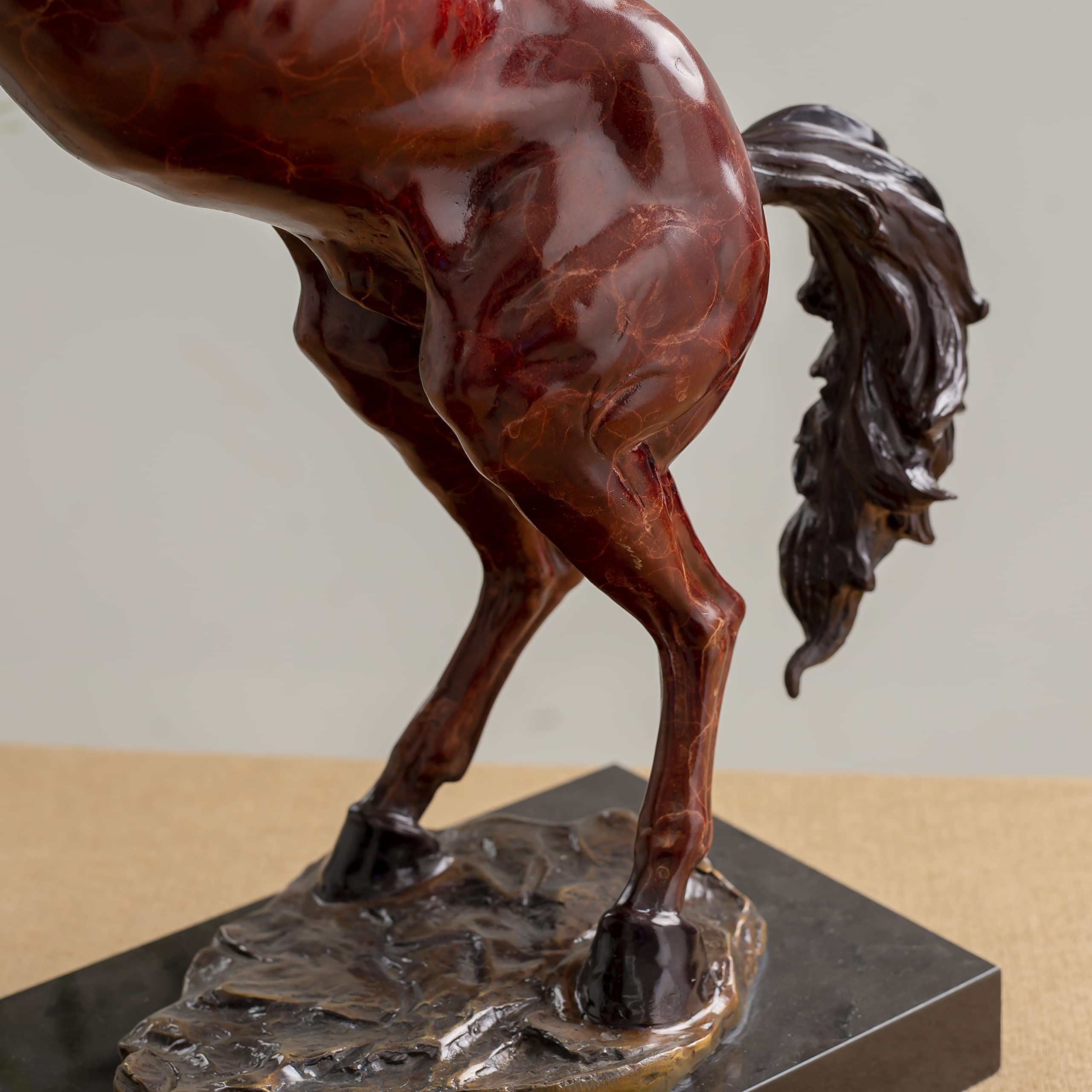 Full body angle view of red bronze rearing stallion sculpture on wooden desk surface