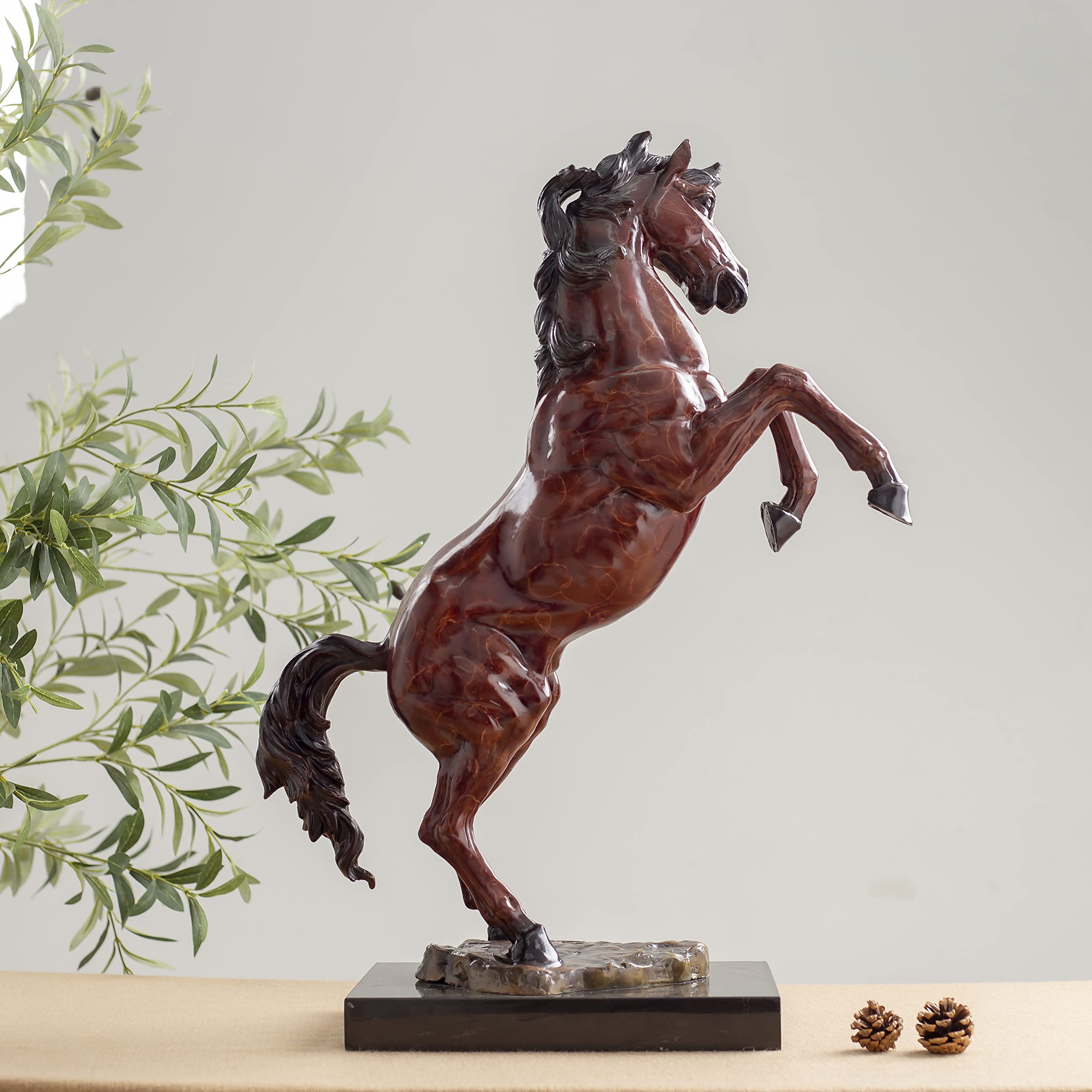 Red bronze rearing stallion sculpture angle view displayed with greenery decor