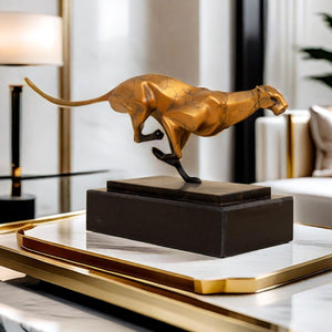 Gold running cheetah sculpture styled on indoor coffee table as luxury home decor