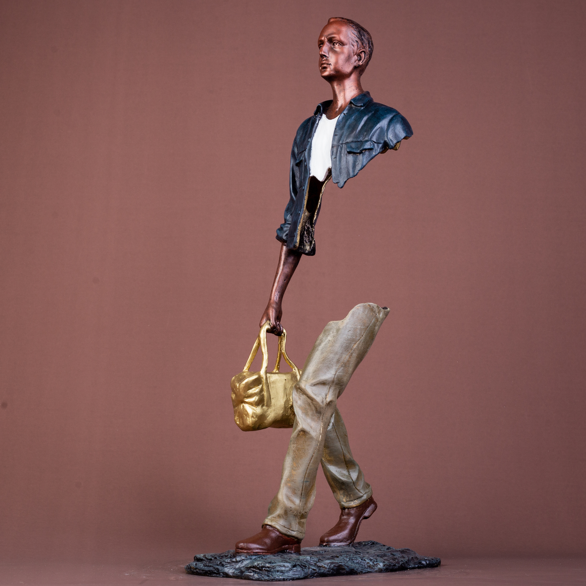 Detailed shot of the polished golden bag accent on the navy blue traveler bronze sculpture.