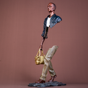 Detailed shot of the polished golden bag accent on the navy blue traveler bronze sculpture.