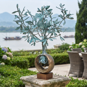 1-meter handcrafted bronze olive tree sculpture displayed on a stone pedestal in a luxury American riverside courtyard with scenic mountain views.