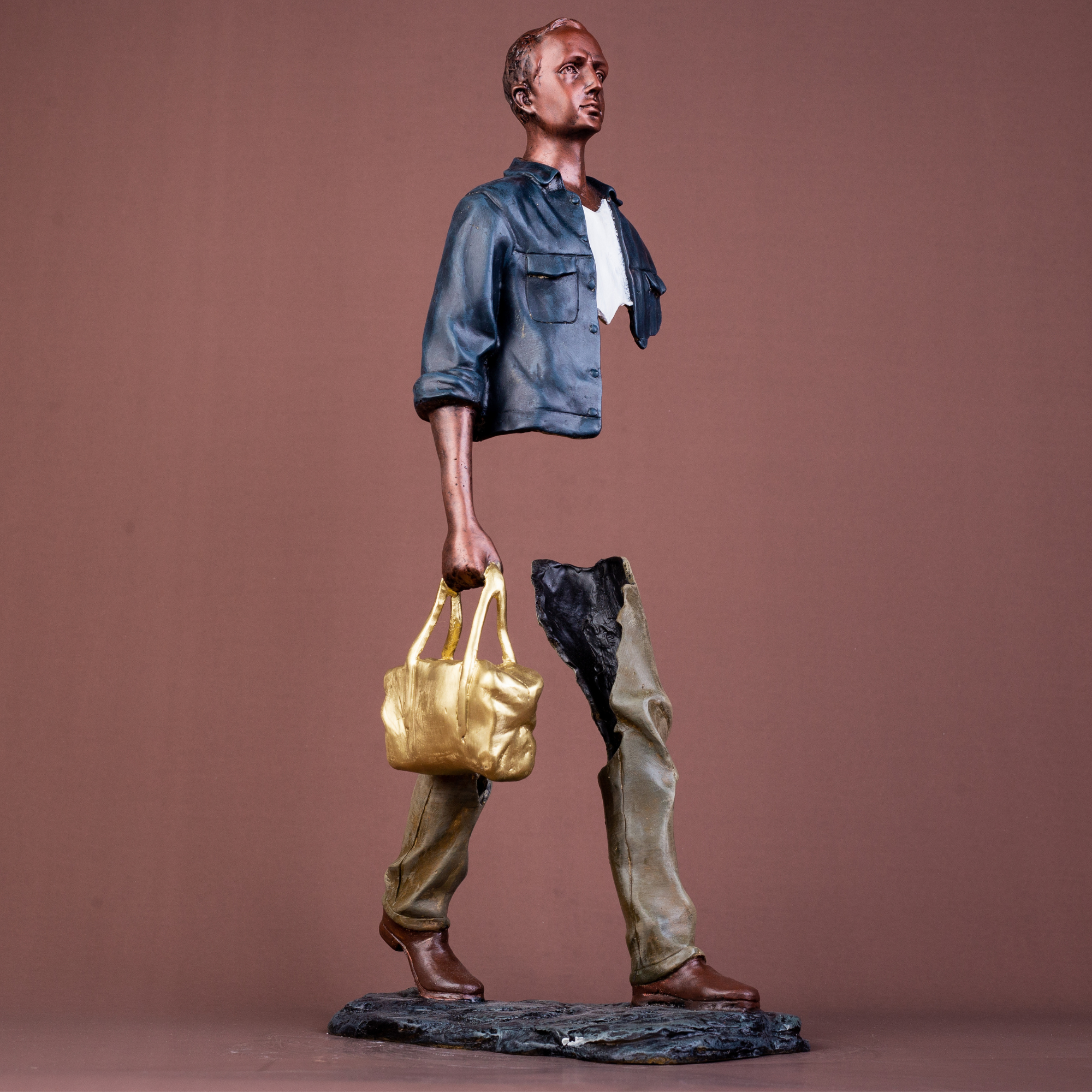 Side profile of the surrealist hollow-body bronze traveler statue in deep navy blue.