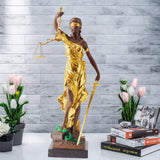 Large gold bronze Lady Justice Themis statue displayed against outdoor white wall front view