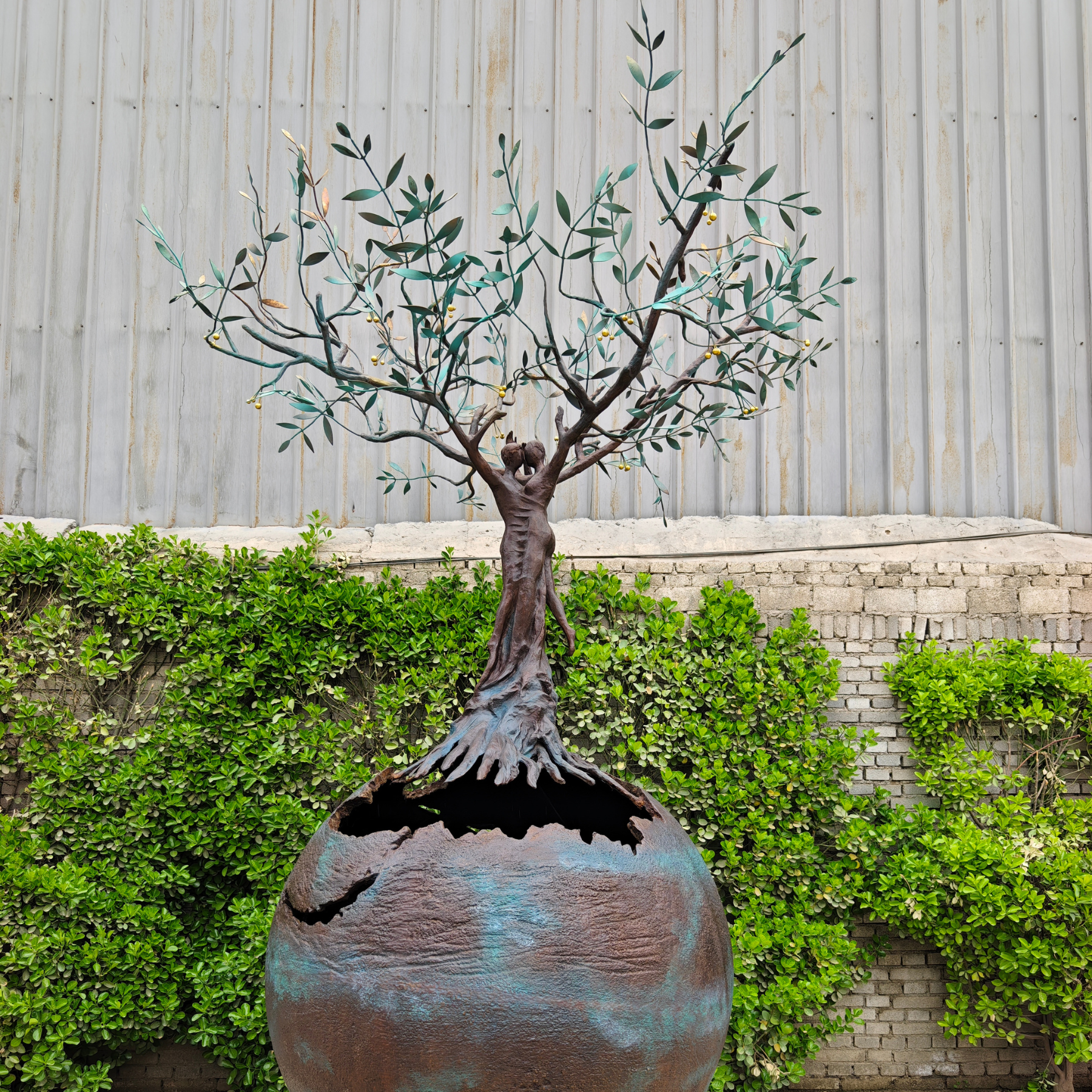 Close-up shot of the exquisite hand-forged olive tree branches and textured bronze globe in our metal art workshop during production.