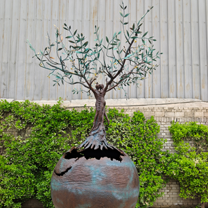 Close-up shot of the exquisite hand-forged olive tree branches and textured bronze globe in our metal art workshop during production.