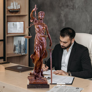 Large gold bronze Lady Justice Themis statue in male lawyer study office bookshelf setting