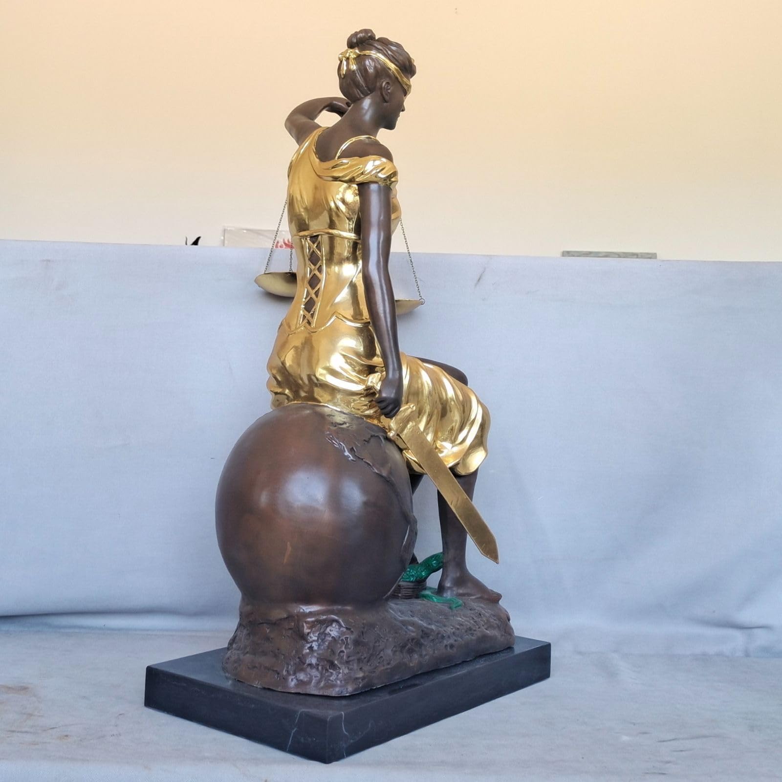 Front angle view of large gold bronze Lady Justice Themis seated sculpture on marble base