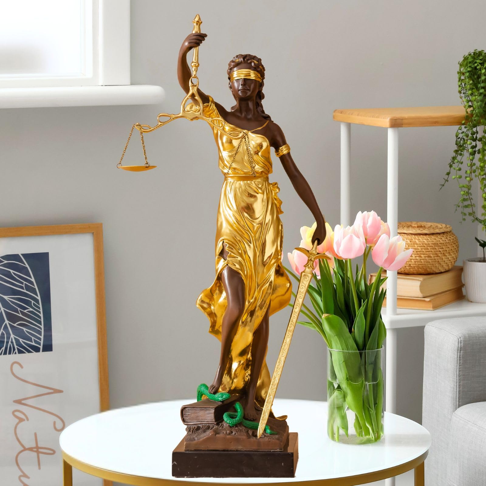Large gold bronze Lady Justice Themis statue on side table styled with floral arrangement in home decor