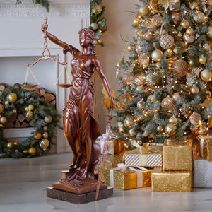 Large red bronze Lady Justice Themis statue displayed beside Christmas tree as holiday gift