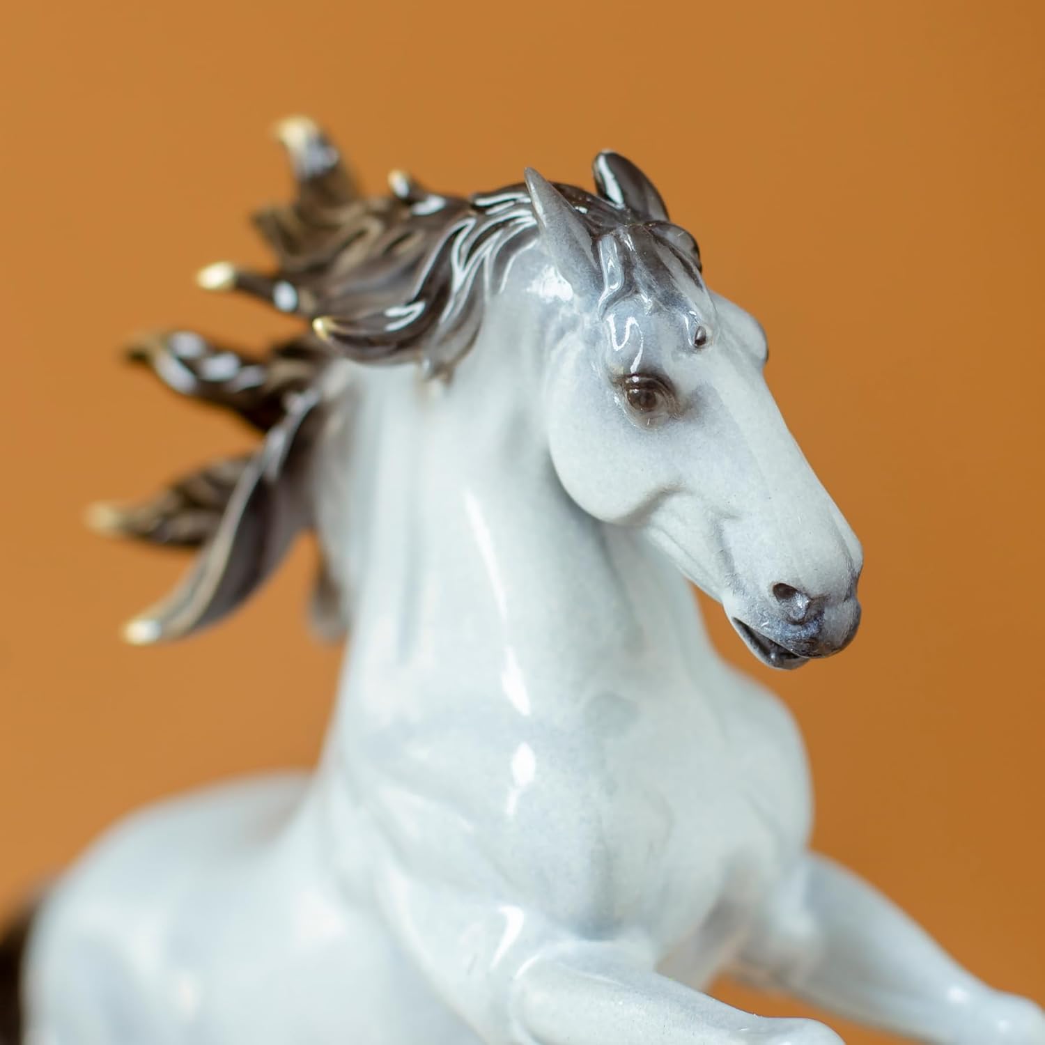 Close-up detail of pearl white rearing horse bronze sculpture head showing dark mane contrast