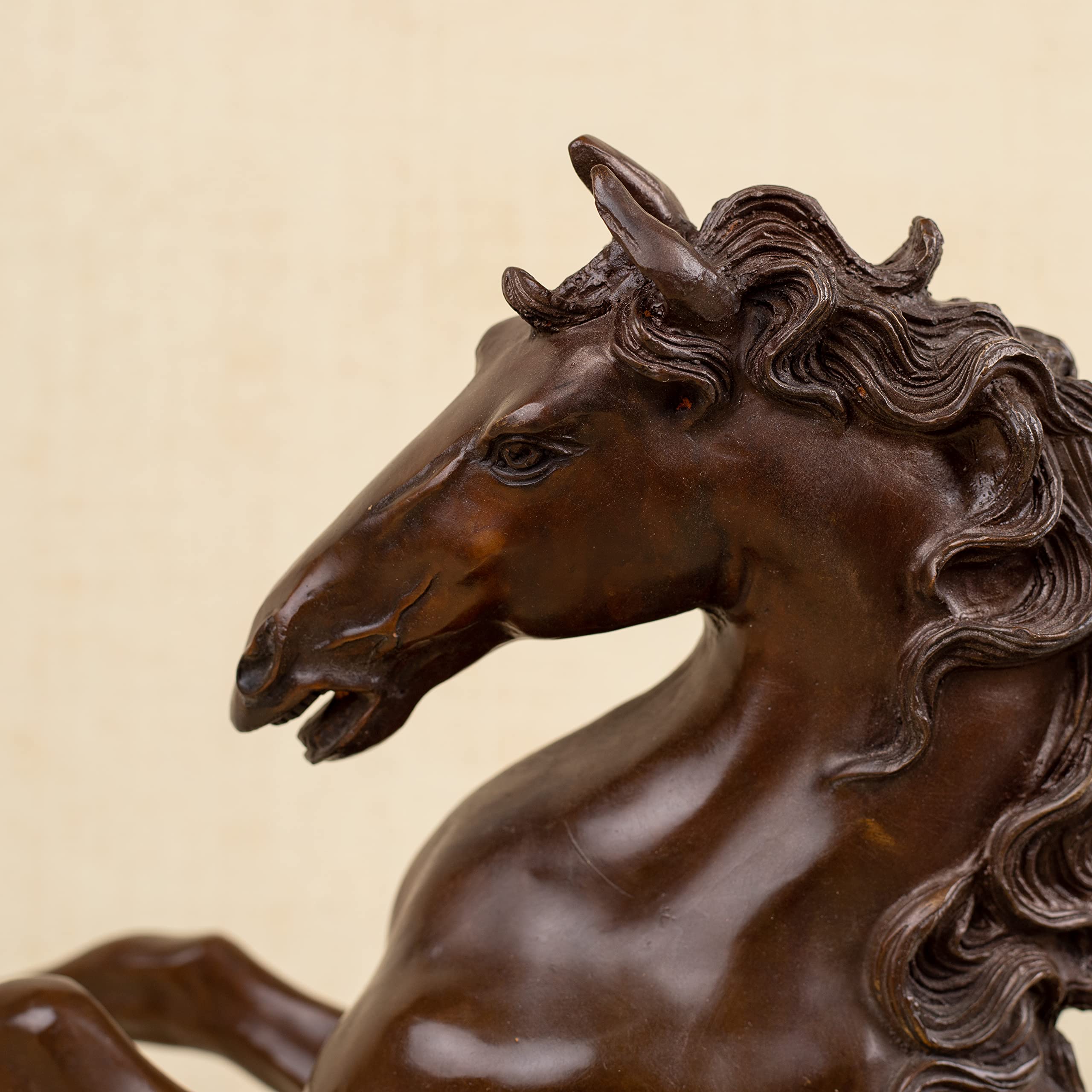 Close-up front detail of bronze rearing stallion sculpture head showing flowing mane texture