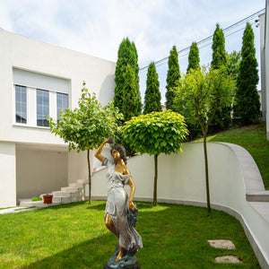Pomona goddess bronze statue displayed on garden lawn surrounded by green plants as outdoor sculpture