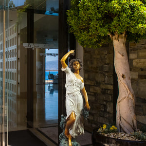 Pomona goddess bronze statue placed at luxury home entrance beside architectural columns as garden art