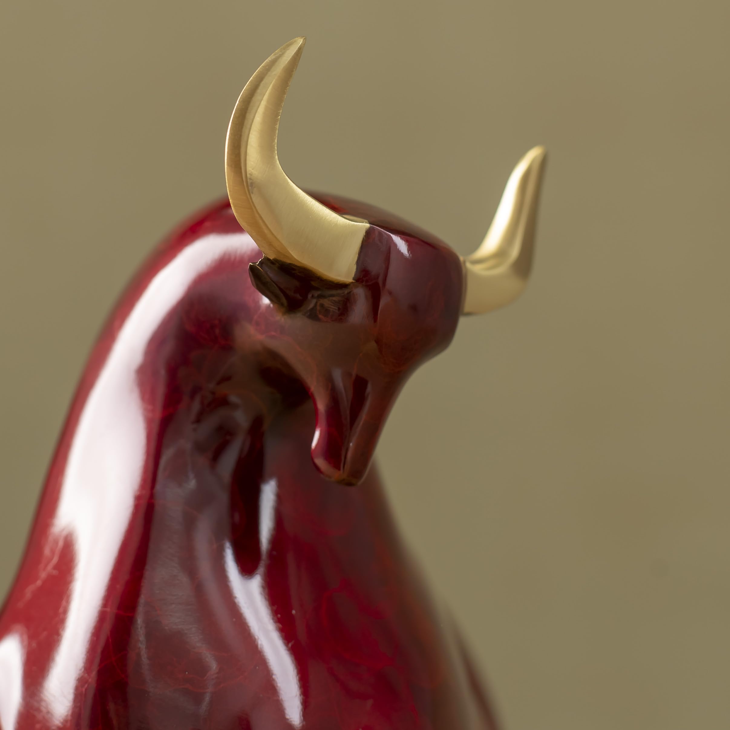 Artistic red enamel glaze texture on charging bull figurine.