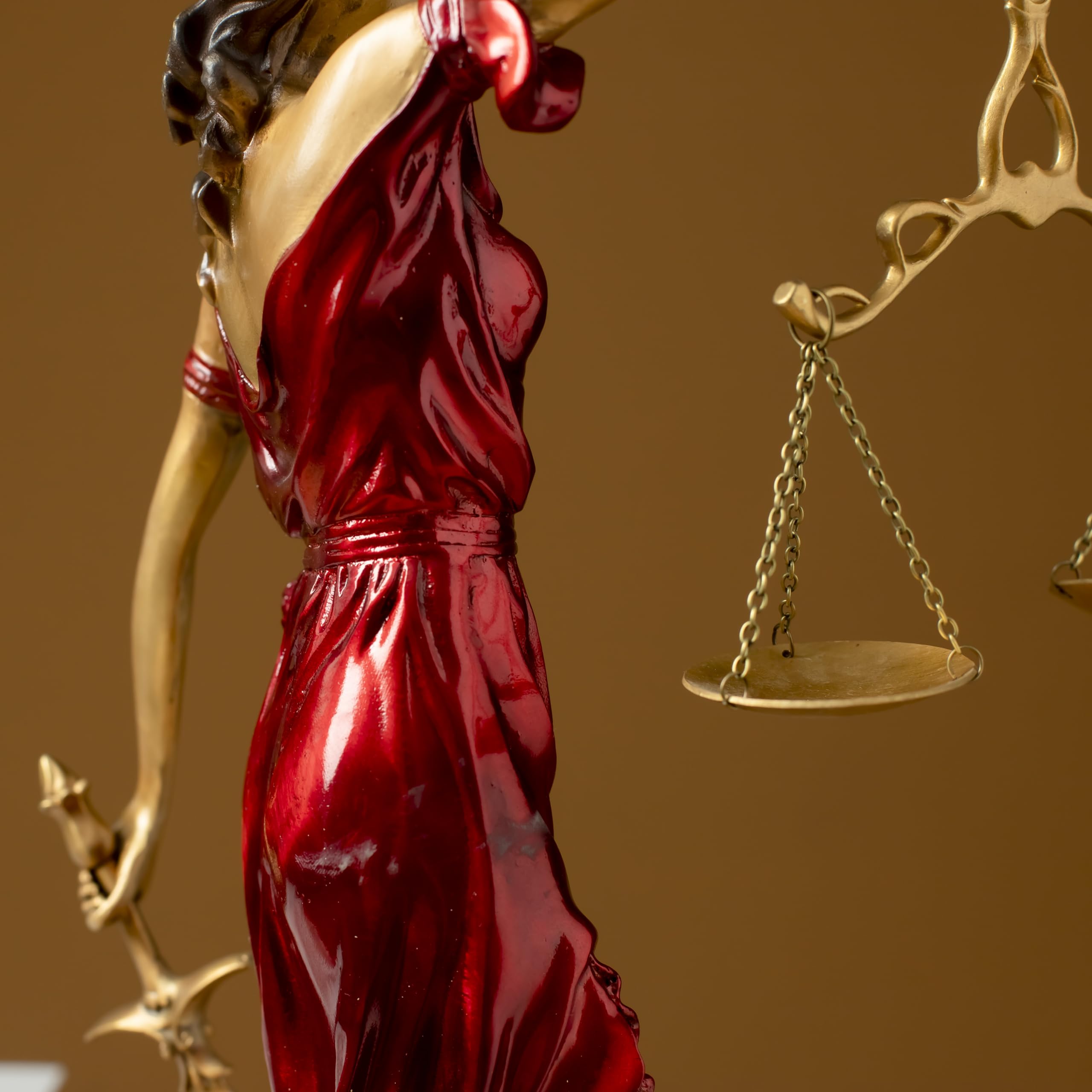 Full body side view of red Lady Justice Themis statue on brown background showing flowing robe