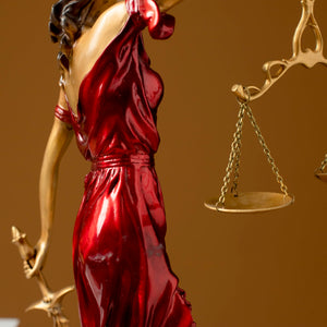 Full body side view of red Lady Justice Themis statue on brown background showing flowing robe