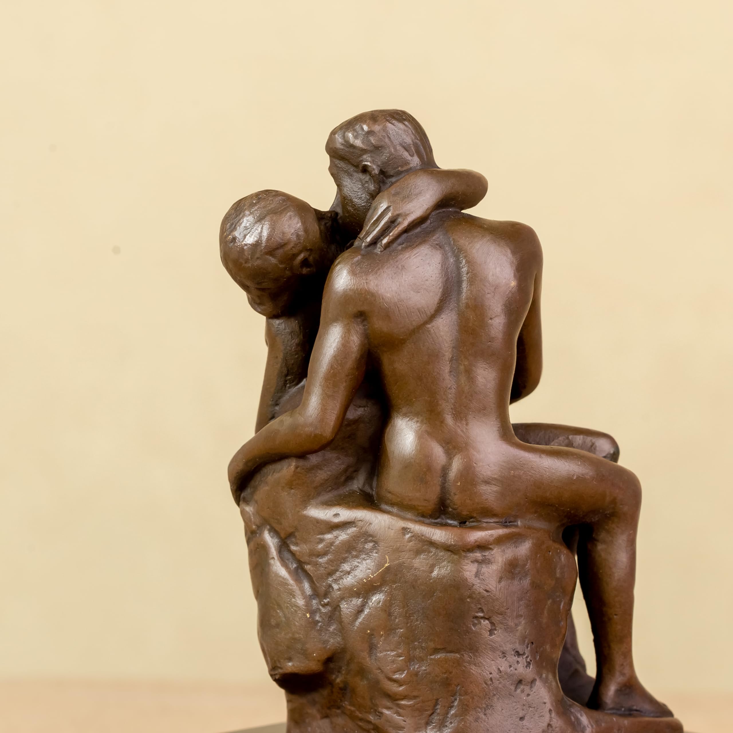 Rodin The Kiss bronze statue side view on warm beige background displaying lovers embrace detail
